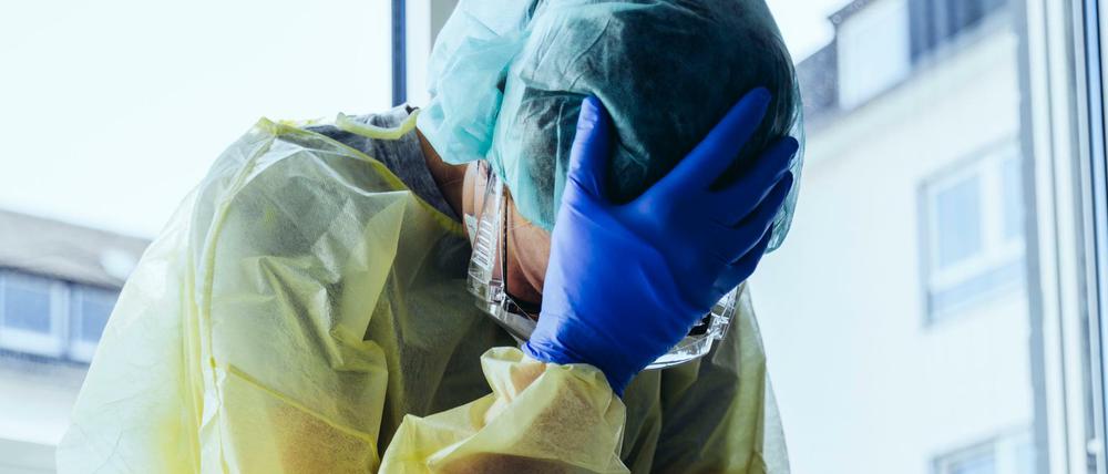 Aufreibende Arbeit: Ein erschöpfter Krankenhaus-Mitarbeiter in Schutzkleidung gegen eine Corona-Infektion. (Symbolbild)