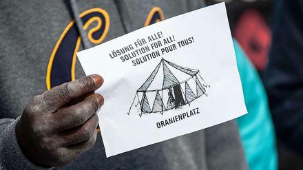Ein Flüchtling hält ein Protestpapier.