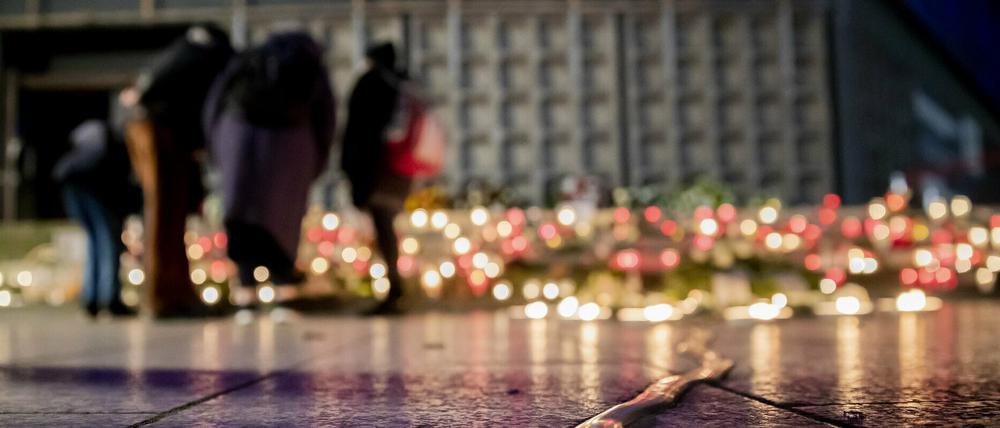 Menschen stehen bei der Gedenkfeier am vierten Jahrestag des islamistischen Anschlags 2020 auf den Weihnachtsmarkt am Breitscheidplatz am Mahnmal „Goldener Riss·, an dem viele Kerzen brennen.