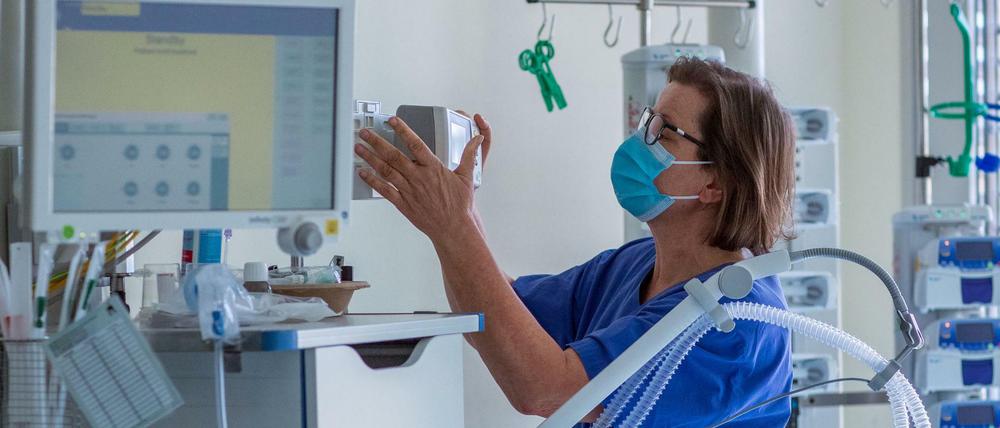 Eine Krankenschwester prüft ein Beatmungsgerät in einem Zimmer einer Intensivstation.