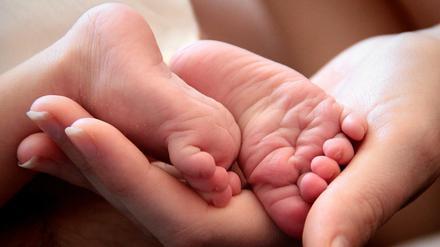Eine Mutter hält die Füße ihrer neugeborenen Tochter. Symbolbild. 