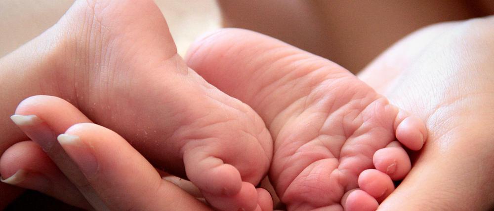 Eine Mutter hält die Füße ihrer neugeborenen Tochter. Symbolbild. 