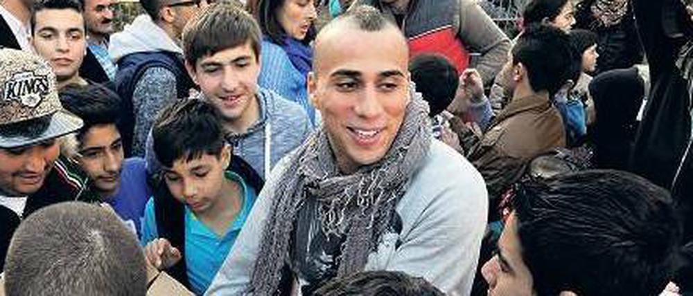 Autogramme vom Fußball-Profi. Änis Ben-Hatira spricht mit Flüchtlingskindern auf dem Bolzplatz.