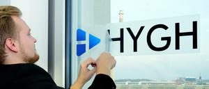 HYGH-Hardware-Chef Antonius Link klebt einen Aufkleber mit Firmenlogo an ein Bürofenster.