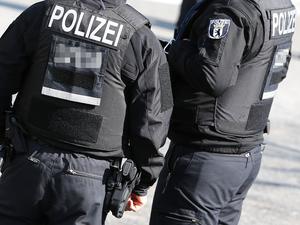 Polizei Symbolbild Polizisten von hinten mit Schusswaffe und kugelsicheren Westen.