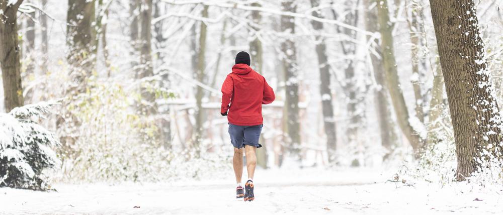 Ein Mann läuft im Dezember 2021 durch den verschneiten Tiergarten.
