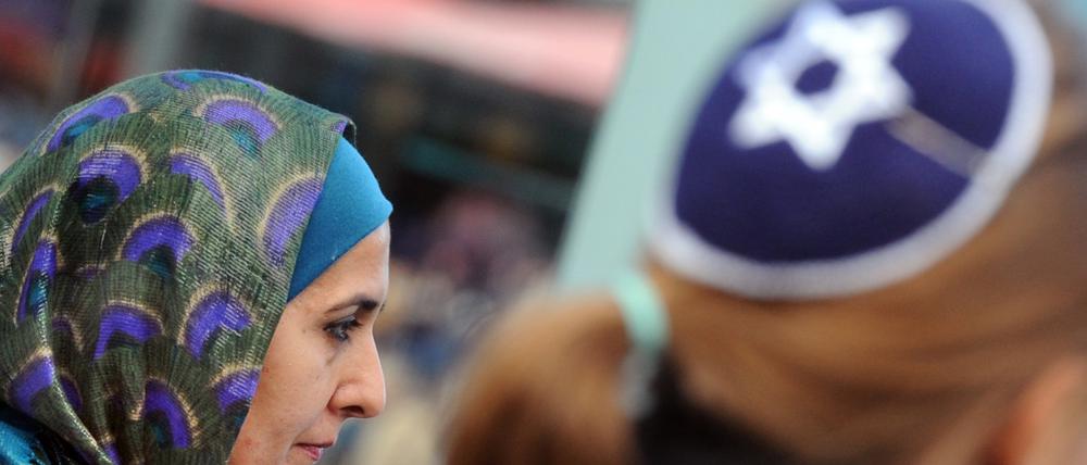 Eine Muslimin mit Kopftuch und eine junge Frau mit Kippa nehmen in Berlin gemeinsam an einer Demonstration teil