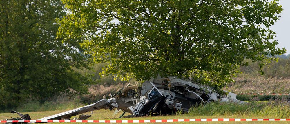 Brandenburg, Zehdenick: Der Wrack eines Kleinflugzeugs liegt nach einem Absturz auf einem Feld zwischen dem Ortsteil Badingen und Gransee hinter einem Absperrband der Polizei. 