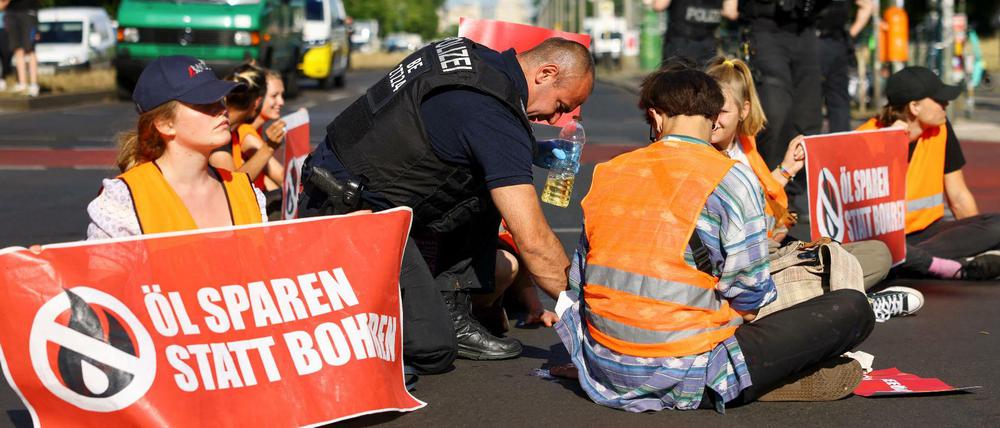 Festgeklebt auf der Fahrbahn: Ein Polizist versucht die Hand eines Aktivisten vom Asphalt am Frankfurter Tor zu lösen.