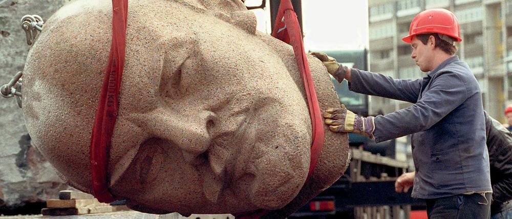 Ein Arbeiter steht am 13.11.1991 während der Abrissarbeiten des ehemaligen Lenindenkmals in Berlin neben dem Kopf des Monuments.
