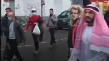 Rechts im Bild der Youtuber Fayez Kanfash, links neben ihm zerrt er die Person mit Macron-Maske hinter sich her. Das Video wurde von einem Passanten aufgenommen.