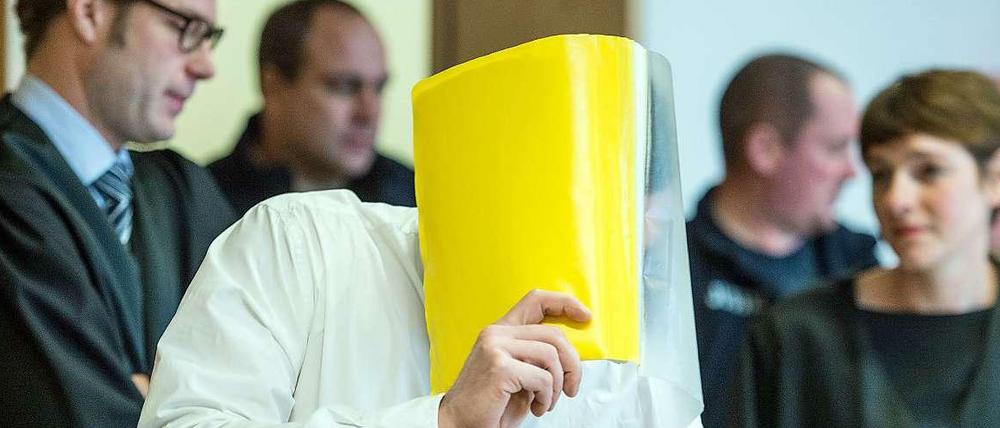 Der Angeklagte Mario K. verdeckt sein Gesicht im "Maskenmann"-Prozess im Landgericht in Frankfurt (Oder).