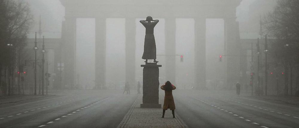 Eine Passantin fotografiert im Nebel das Brandenburger Tor. 