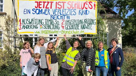 Eltern, Schüler:innen und Lehrende der Giesensdorfer Grundschule in Berlin mit einem Protestplakat für sichere Schulwege.