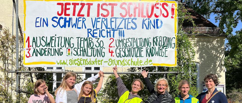 Eltern, Schüler:innen und Lehrende der Giesensdorfer Grundschule in Berlin mit einem Protestplakat für sichere Schulwege.