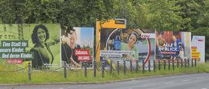 Wahlplakate verschiedener Paeteien stehen in einer Reihe auf einem Grünstreifen in Berlin.