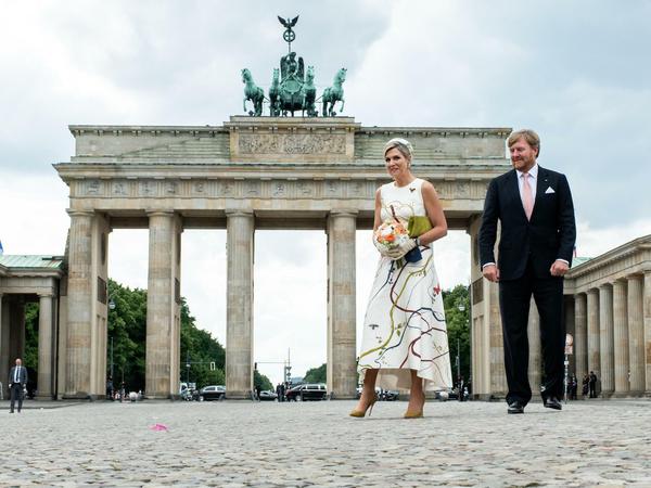 König Willem-Alexander der Niederlande und Königin Maxima gehen über den Pariser Platz, im Hintergrund das  Brandenburger Tor.