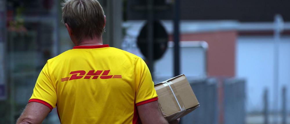 Ein Paketzustellerder von Deutsche Post DHL liefert ein Paket aus.