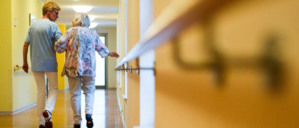 Mit Herz: Eine Pflegekraft begleitet eine ältere Dame im Pflegeheim über einen Korridor.