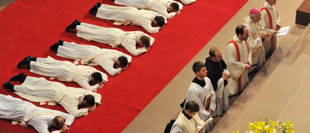 Priesteranwärter liegen während ihrer Weihe zum Priester als Zeichen der Demut bäuchlings auf einem roten Teppich im Freiburger Münster.