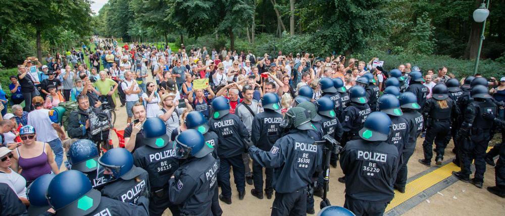 Polizisten drängen bei einem Protest gegen die Corona-Maßnahmen an der Siegessäule Menschen in den Tiergarten ab.