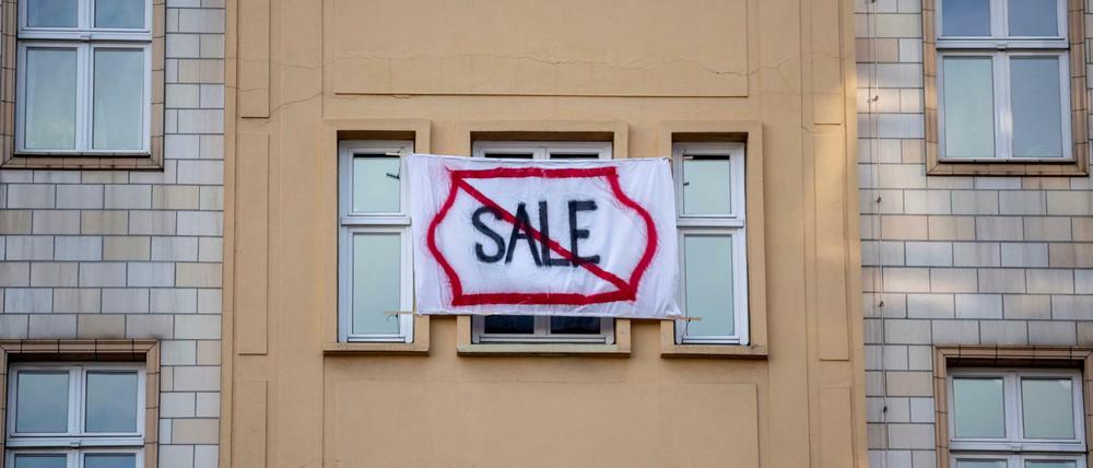 Ein Plakat gegen den Verkauf von Mietwohnungen an die Deutsche Wohnen an einer Fassade in der Karl-Marx-Allee. 