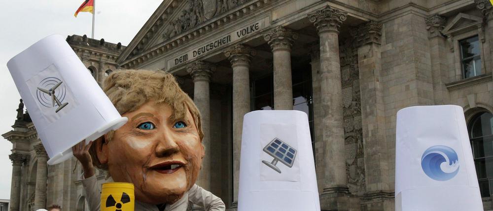 Das Organisationsbündnis "Klima-Allianz" protestiert am 8.09.2010 vor dem Bundestag gegen das Energiekonzept der Bundesregierung. Dabei zeigt eine Merkel-Puppe "Hütchenspielertricks". Unter drei Gefäßen, die mit Symbolen erneuerbarer Energien bedruckt sind, kommen Atommüllfässer, Kohle- und Kernkraftwerke zum Vorschein.