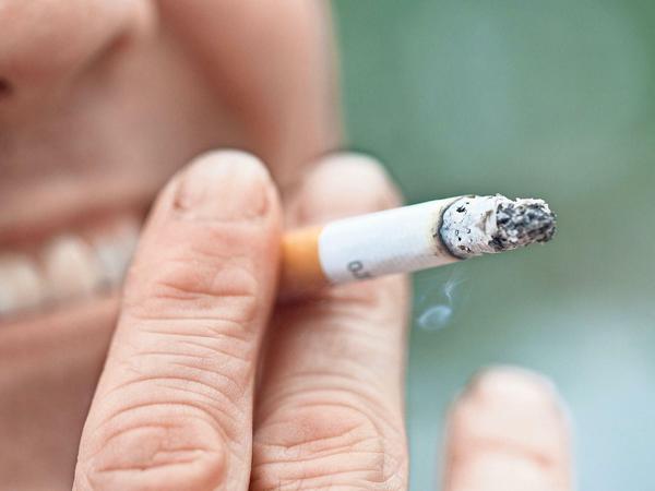 Ein Mann raucht eine Zigarette. Raucher haben ein erhöhtes Risiko, mit den Zähnen zu knirschen.