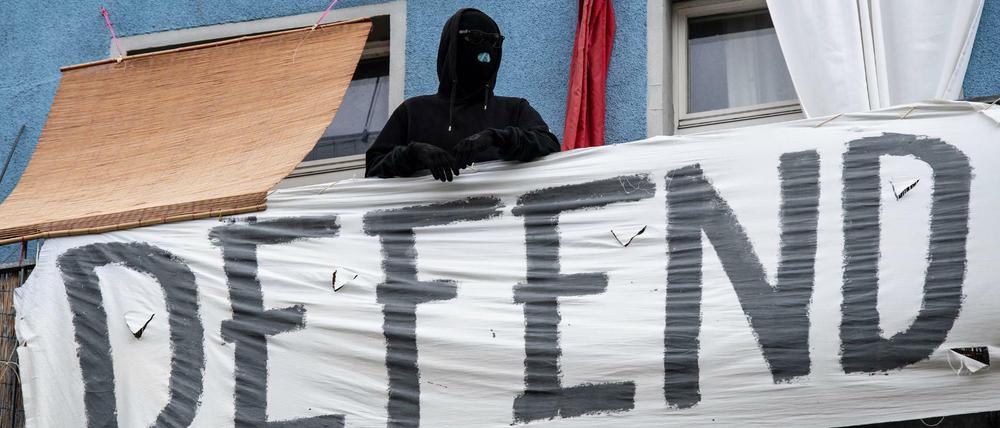 Was wird hier verteidigt? Ein Vermummter und ein Transparent auf einem Balkon in der Rigaer Straße.