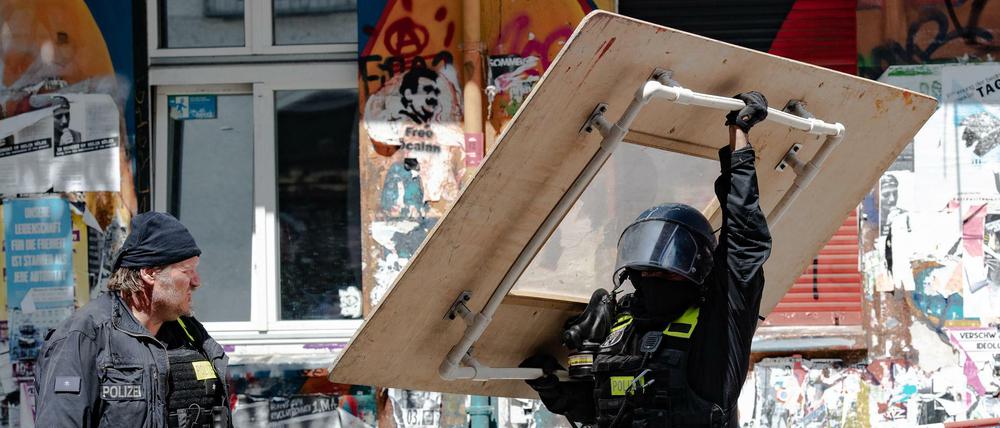 Ein Polizeibeamter trägt ein übergroßes Schutzschild aus dem Haus Rigaer Straße 94.