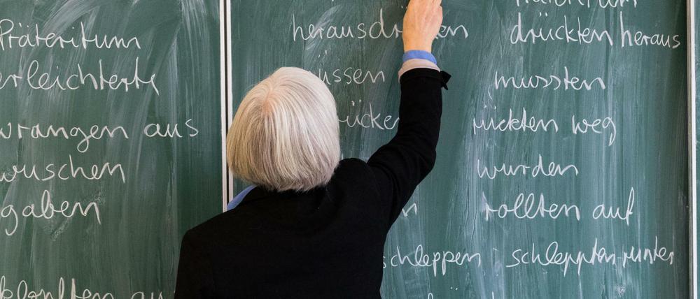 Eine Lehrerin steht in einem Klassenraum an einer Tafel (Symbolbild).
