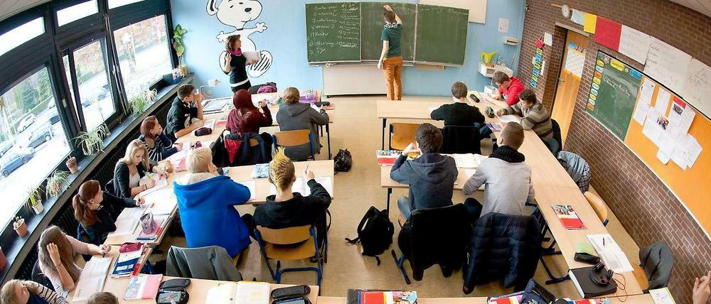 Ein Klassenzimmer mit Schülern, vorn an der Tafel steht die Lehrerin.