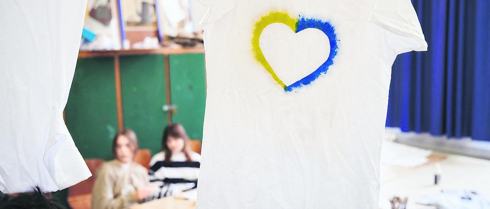 Ein T-Shirt mit einem Herz, umrahmt von den ukrainischen Farben hängt im Klassenraum einer Willkommensklasse am Willy-Graf-Gymnasium in Berlin-Lichterfelde. 