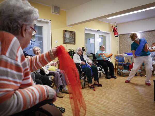 Pflegerin Jeanine Laschinski leitet die Seniorinnen und Senioren fröhlich zu Bewegungen an.