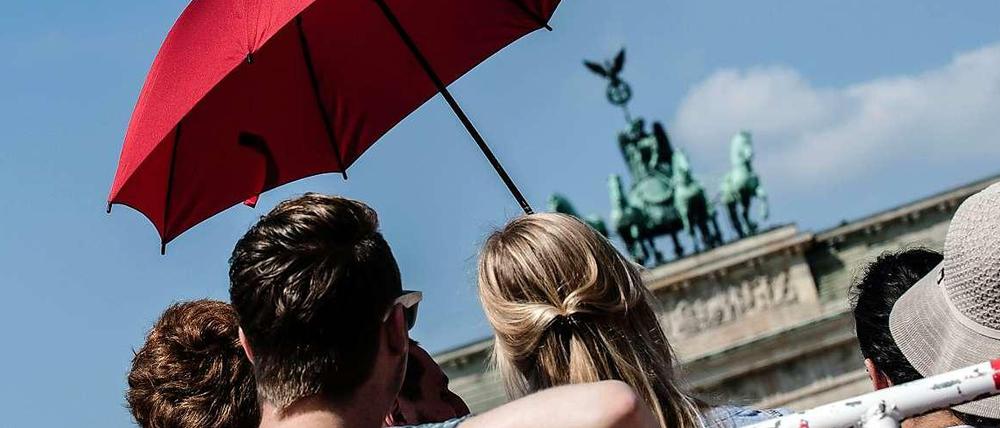 Besucher mit Sonnenschirm vor dem Brandenburger Tor.