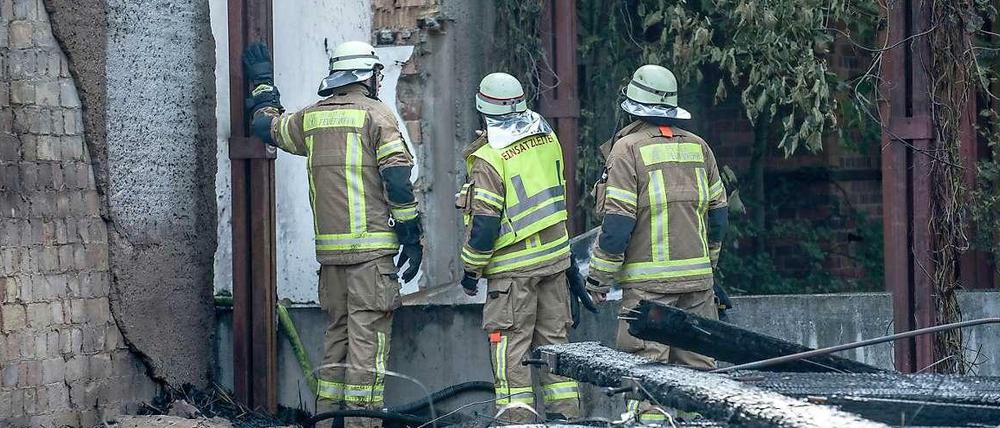 Brandruine: Feuerwehrleute begutachten nach den Löscharbeiten die vom Feuer zerstörten Kulissen-Häuser im Spreepark. 