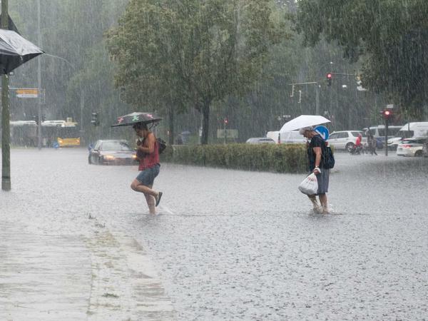 Fußgänger waten durch die überflutete Tiergartenstraße. 