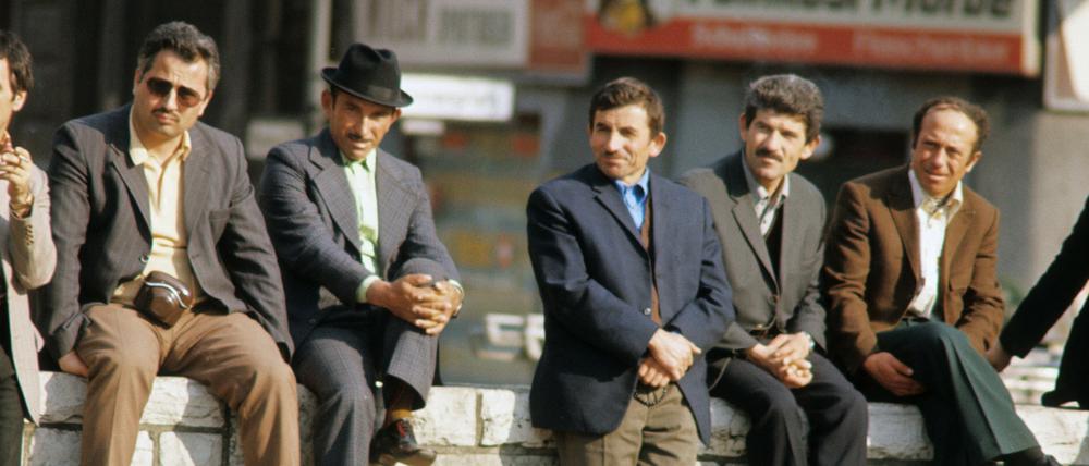 Gastarbeiter sitzen in der Sonne auf einer Mauer in Kreuzberg in den 1970er Jahren