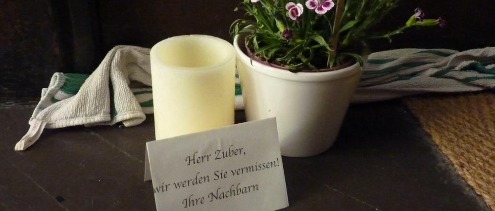 Vor der Wohnungstür des Toten haben Nachbarn eine Blume und eine Kerze aufgestellt.