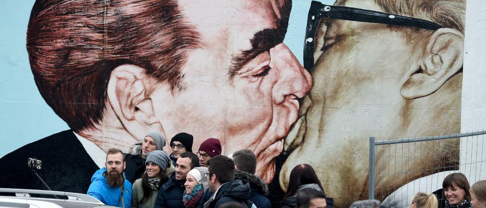 Touristen fotografieren sich vor dem «Bruderkuss zwischen Leonid Breschnew und Erich Honecker» von Dmitri Wladimirowitsch Wrubel.
