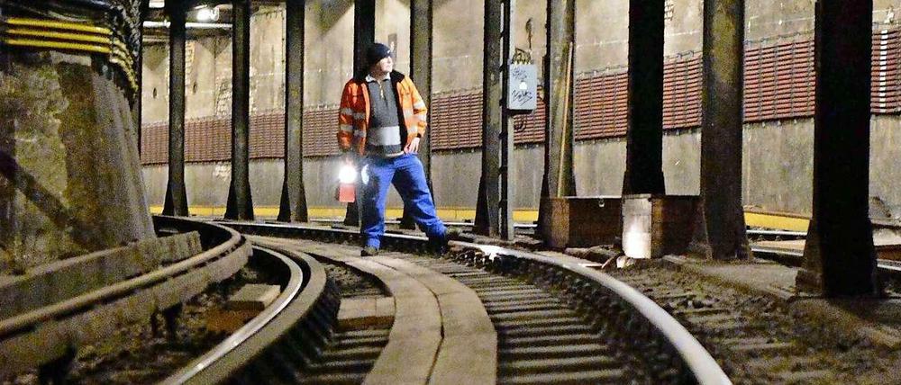 Blick in den Tunnel der U-Bahnlinie 2, in der ein Arbeiter auf den Schienen steht.