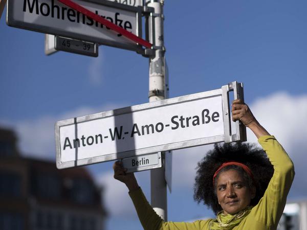 Eine Aktivistin hält bei einer Kundgebung zur Umbenennung der Mohrenstraße ein Straßenschild der „Anton-W.-Amo-Straße" hoch.