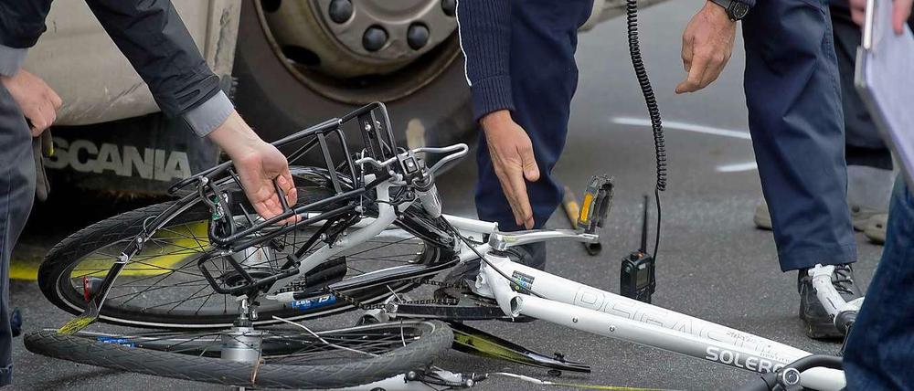 Helfer heben ein kaputtes Fahrrad nach einem Verkehrsunfall auf. 