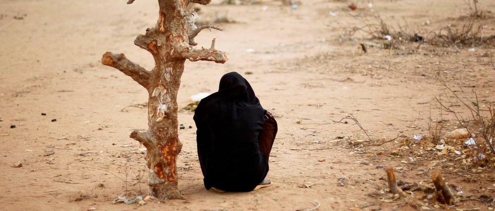 Eine Frau aus Somalia sitzt in der Nähe eines verdorrten Baums.