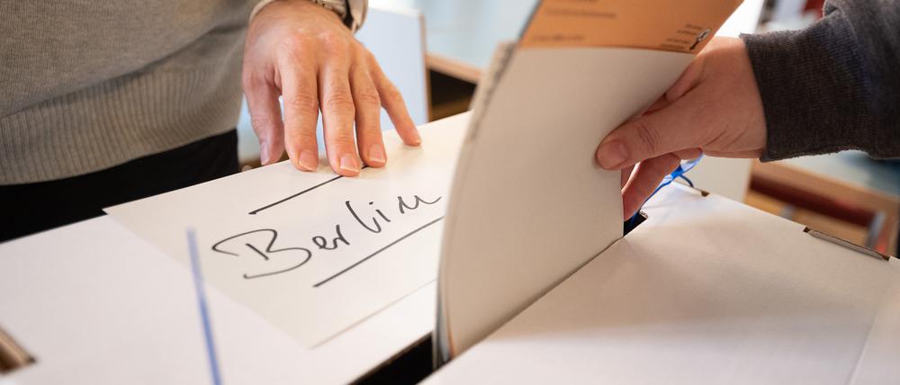 Eine Frau gibt in einem Wahllokal Wahlzettel für die Wahl des Abgeordnetenhauses und den Volksentscheid in Berlin ab.