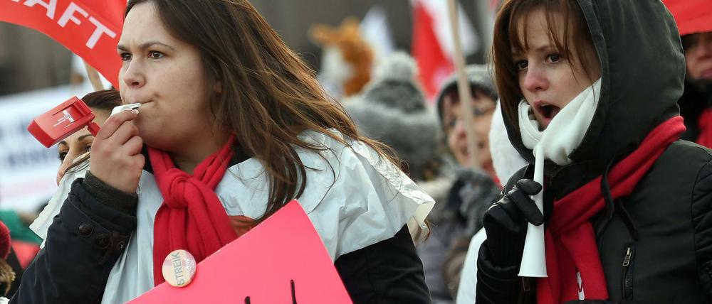 Zwei junge Frauen zeigen beim Streik der Berliner Erzieher und Sozialpädagogen Plakate, die ihren Unmut zum Ausdruck bringen.
