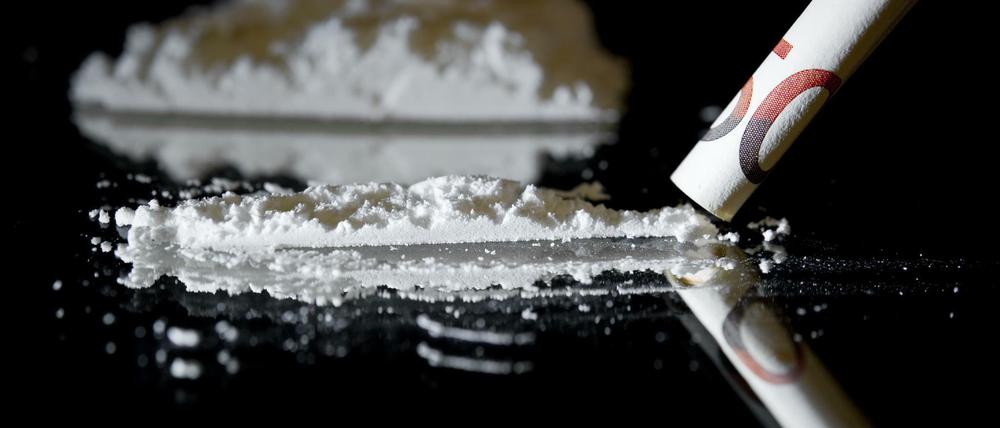 Mit einem zusammengerollten 50-Euro-Geldschein wird ein weißes Pulver, das Kokain imitieren soll, symbolisch konsumiert.