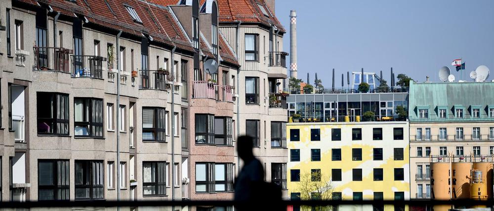 Mietendeckel in Berlin: Ein Mann geht vor der Kulisse von innerstädtischen Wohnhäusern über eine Brücke.