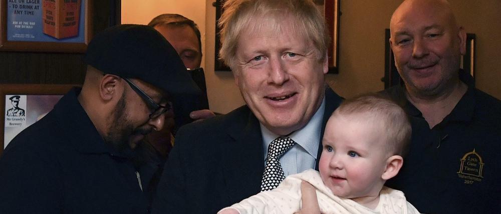 Boris Johnson hält ein Baby auf dem Arm während er sich mit Militärveteranen trifft.