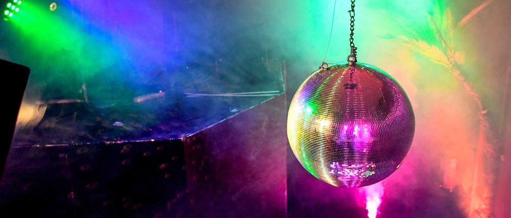 Eine Diskokugel dreht sich in einem Club und reflektiert das einfallende Licht der Scheinwerfer und Lampen. (Archivbild) 